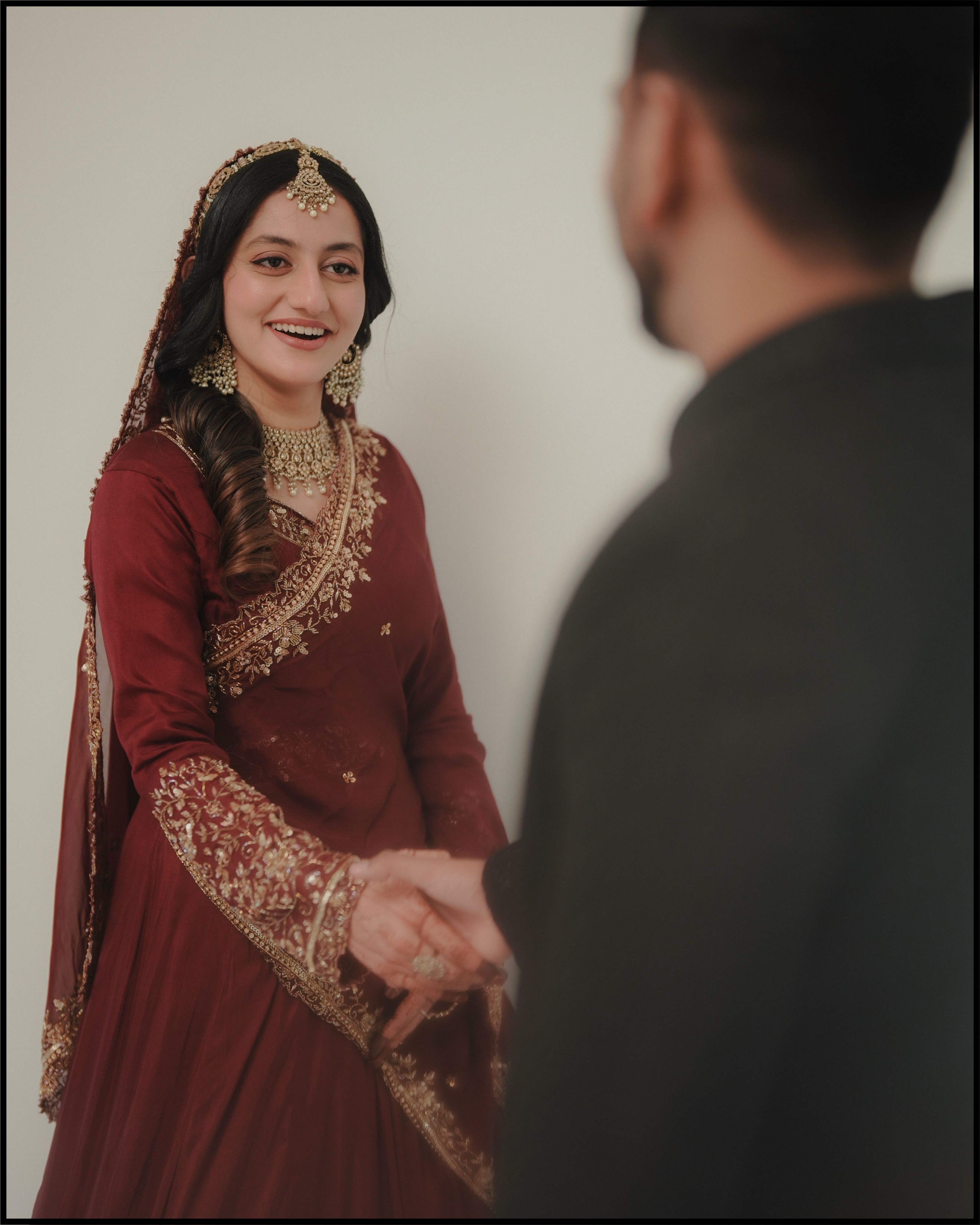 Bride smiling at her partner in maroon wedding attire