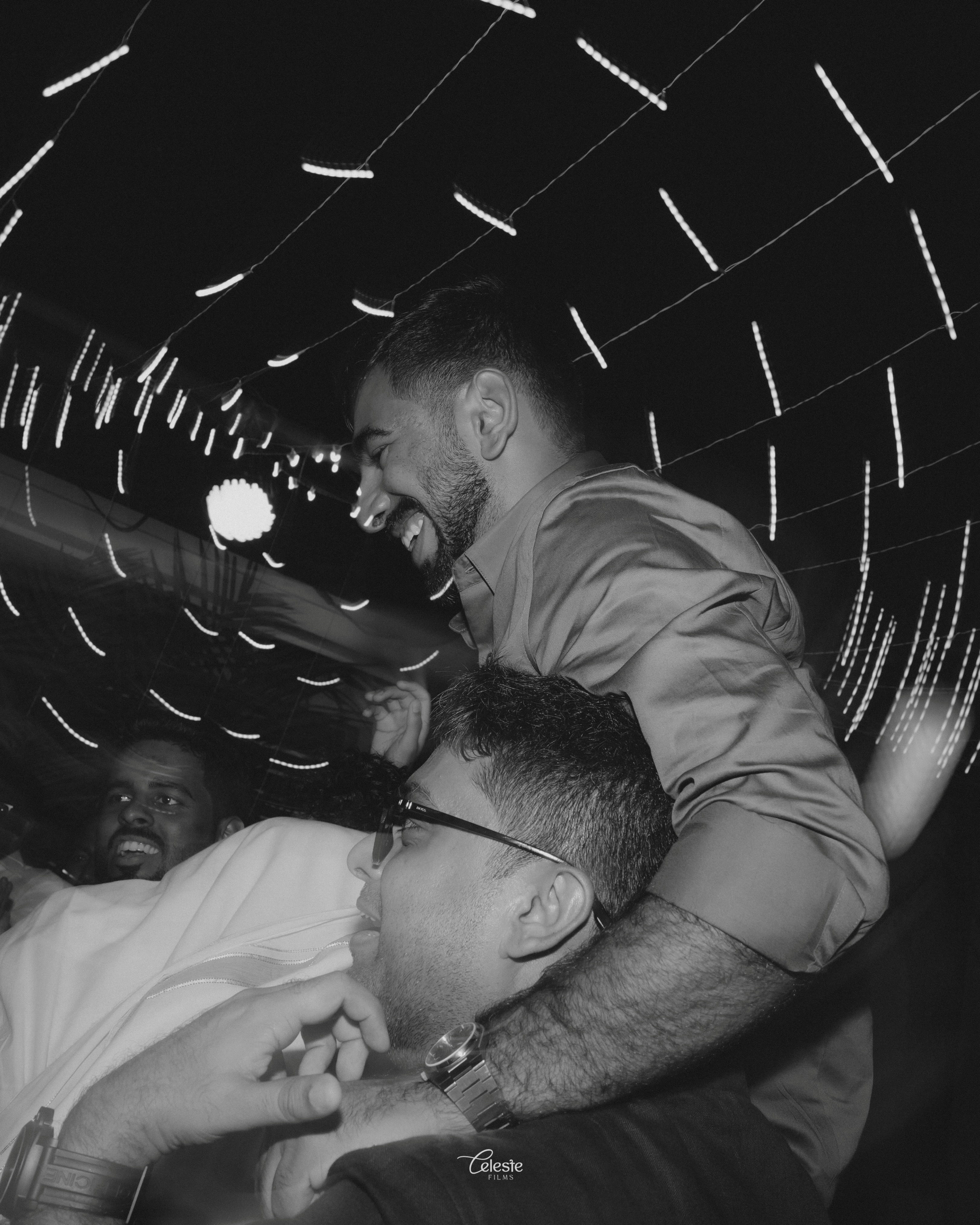 Wedding guests celebrating beneath string lights
