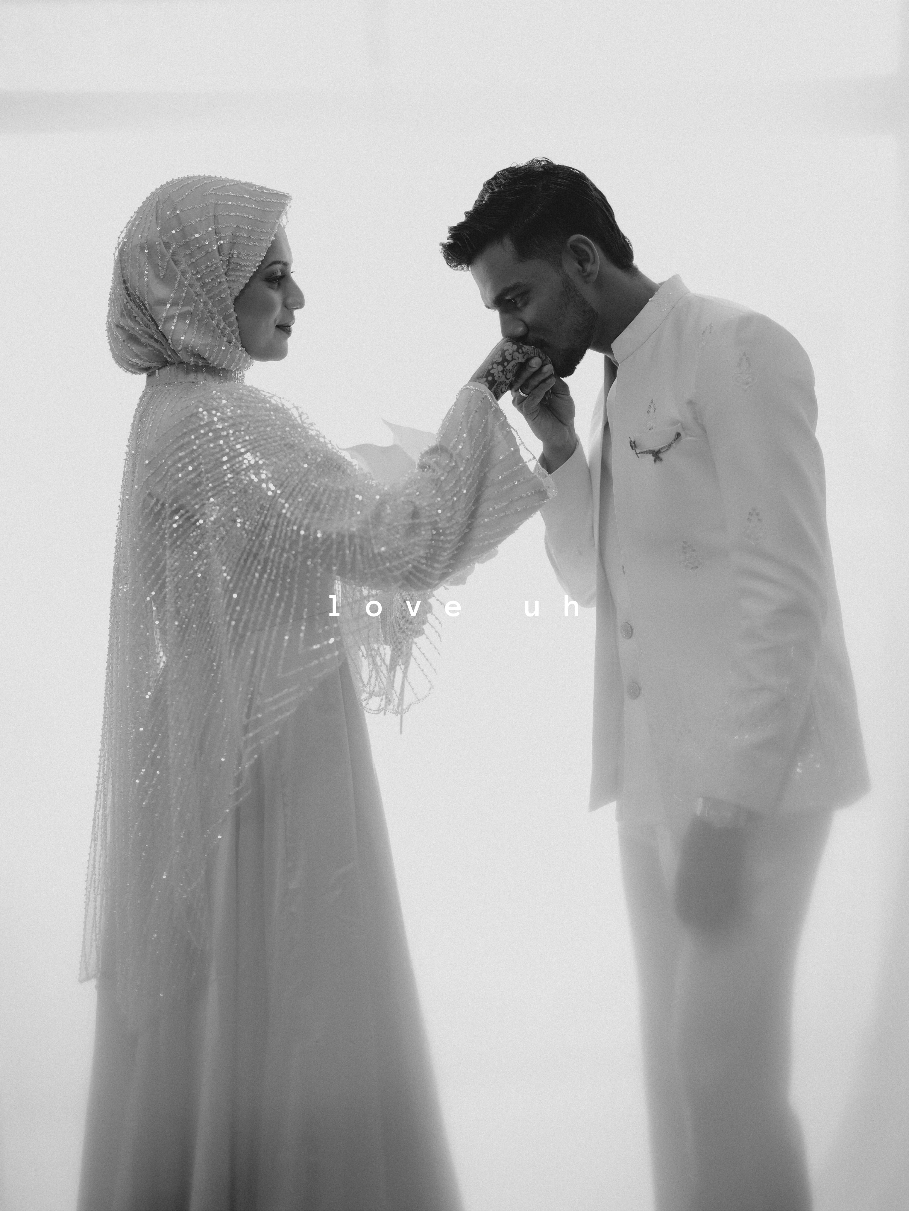 Groom kissing the bride's hand in a black-and-white portrait